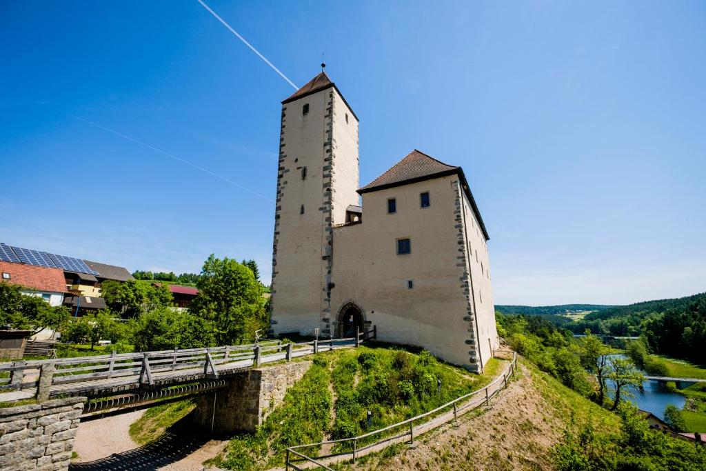 ein Gebäude mit einem Turm auf einem Hügel mit einer Brücke in der Unterkunft Jugendherberge Burg Trausnitz in Trausnitz