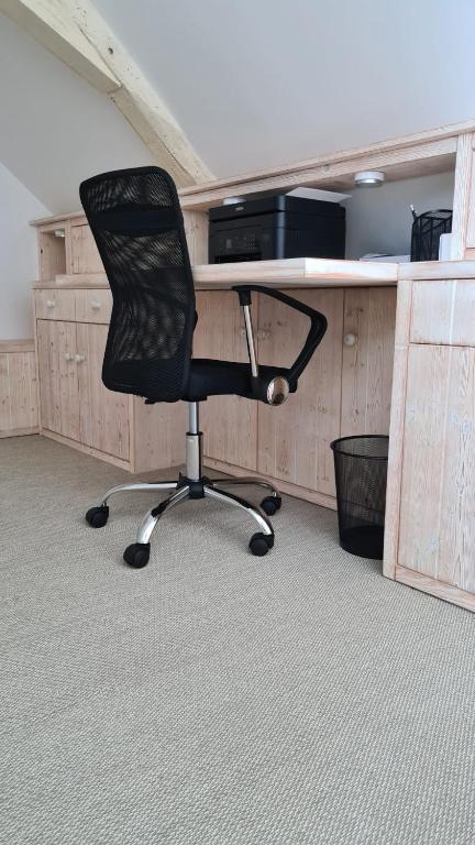 a desk with a black chair in an office at Maison de vacances Daumeray in Daumeray