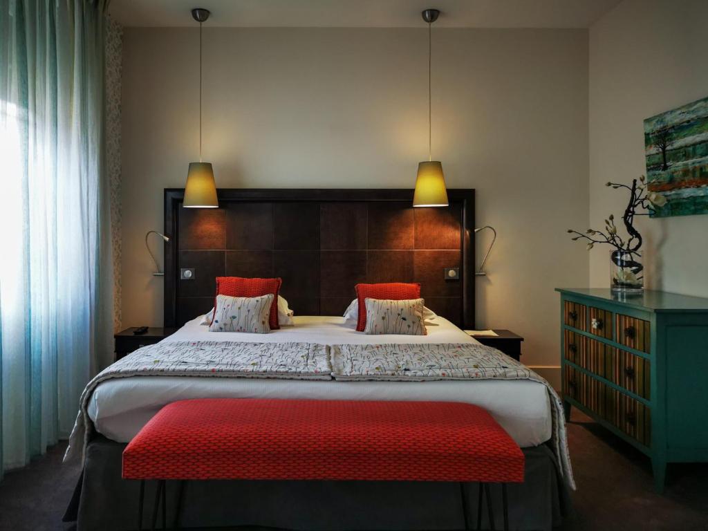 Hôtel Le Griffon d'Or في بورغ أون بريس: غرفة نوم بسرير كبير مع مقاعد حمراء