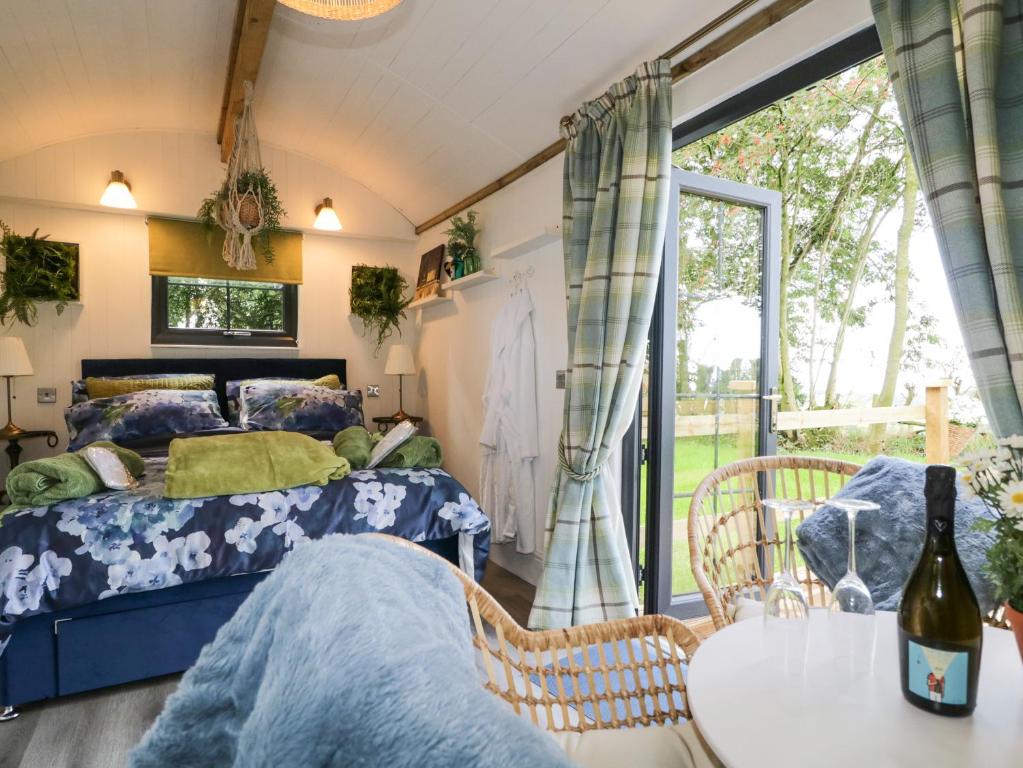 Schlafzimmer mit einem Bett, einem Tisch und einem Fenster in der Unterkunft High Rigg Shepherd's Sunset in Carlisle