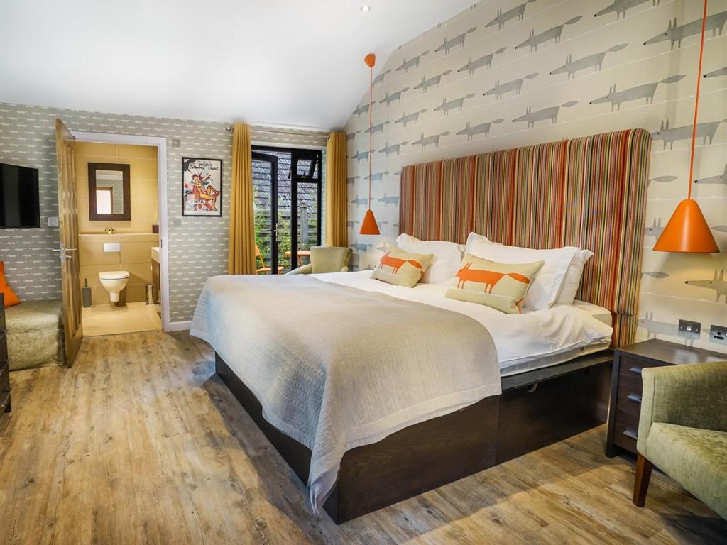 1 dormitorio grande con 1 cama blanca grande con almohadas de color naranja en The Bakery Restaurant with Rooms, en Westerham