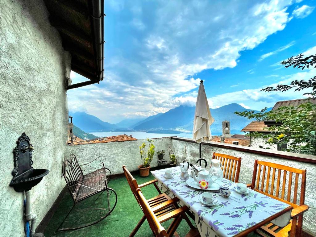 a table and chairs on a balcony with a view of mountains at Casa Brenzio Rustico in Consiglio di Rumo
