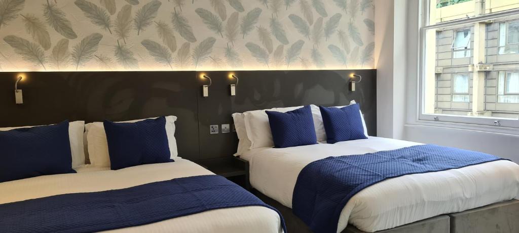 two beds in a room with blue and white at Commodore Hotel in London