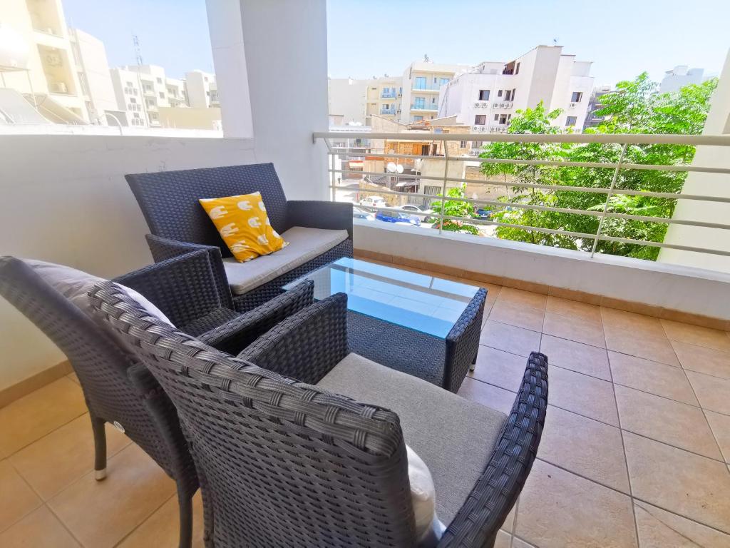 einen Balkon mit Stühlen, einem Tisch und einem Sofa in der Unterkunft Promenade Breeze City Apartment in Larnaka