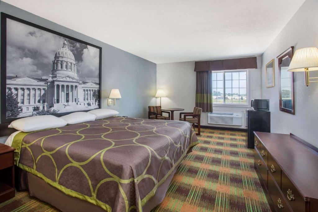a hotel room with a large bed and a building at Super 8 by Wyndham Sweet Springs in Sweet Springs