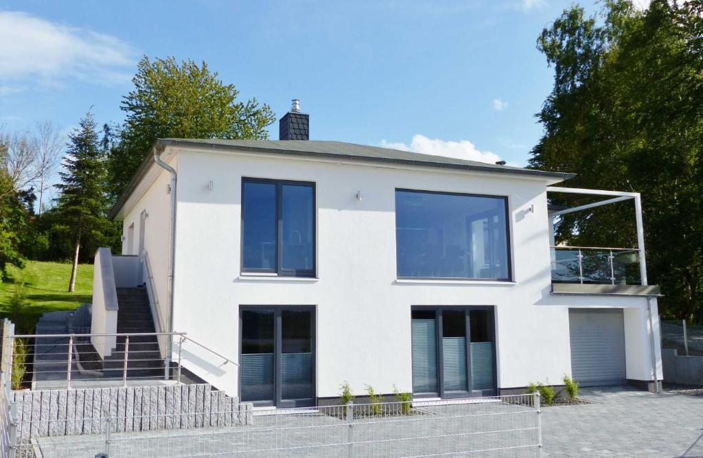 a white house with blue windows at Ferienvilla mit Panoramablick auf den Schmachter See in Binz
