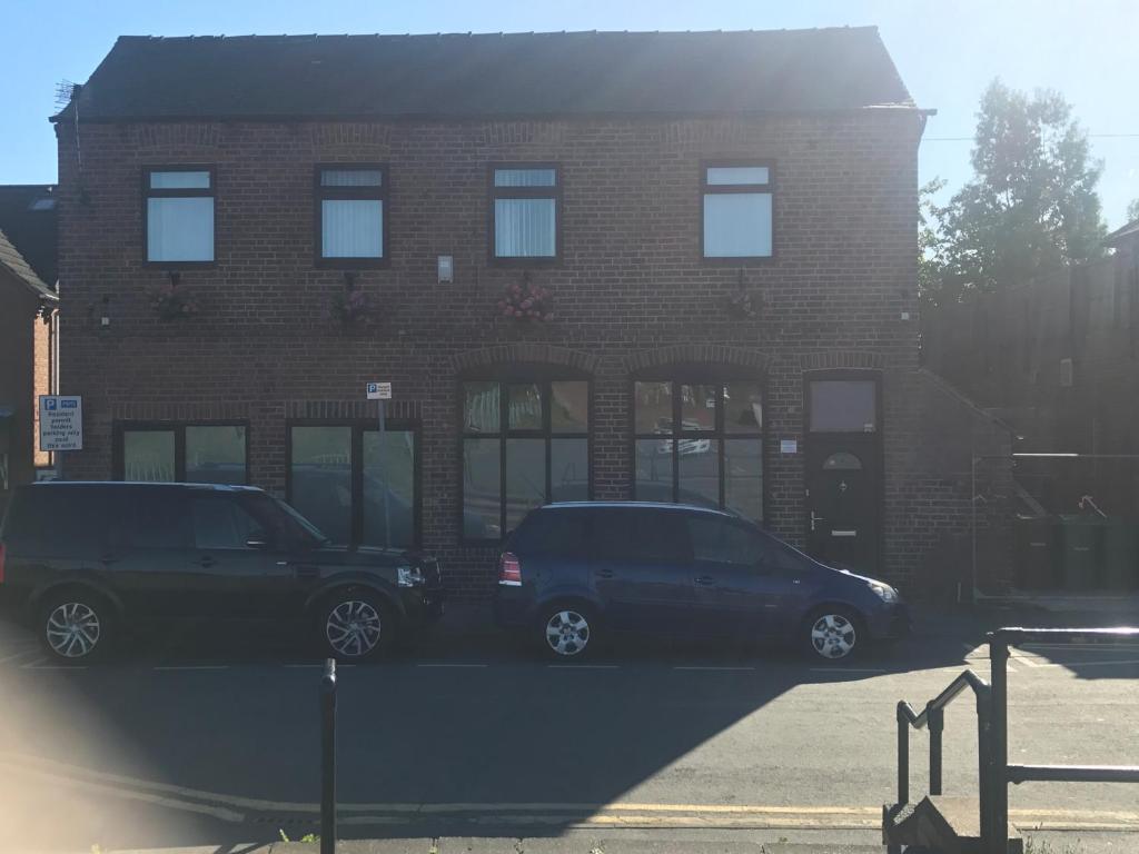 two cars parked in front of a brick building at Home from Home 1 in Castleford