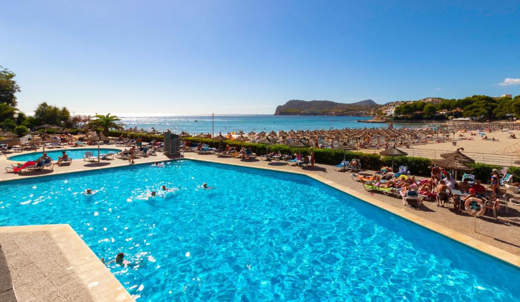 a beach with a pool, chairs, and a pool table at Hotel Vibra Beverly Playa in Paguera