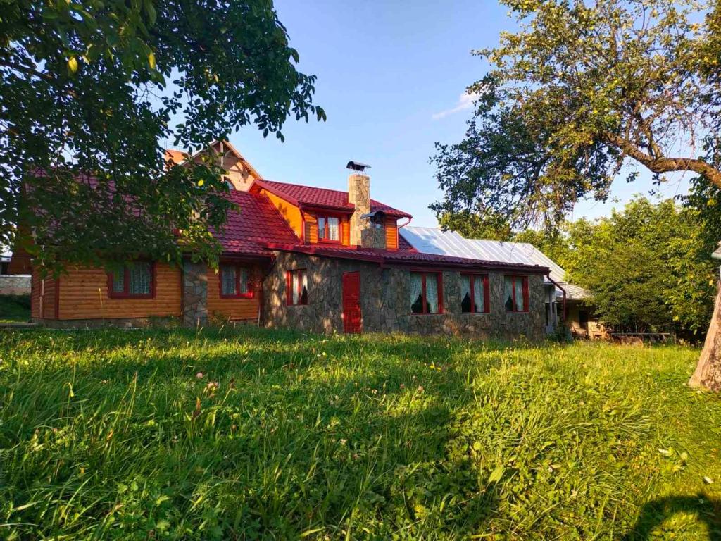 una casa vieja con techo rojo en un campo en Бердо-Хауз en Dilyatyn