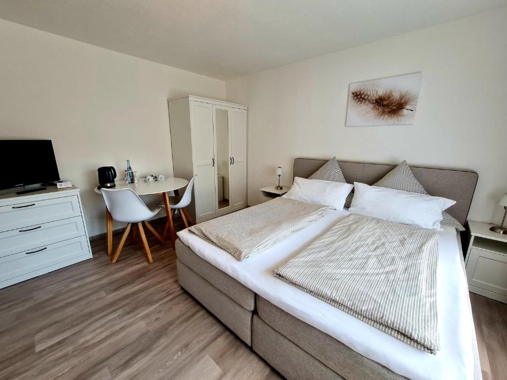 Schlafzimmer mit einem Bett, einem Tisch und einem TV in der Unterkunft Pension Villaggio in Mertesheim