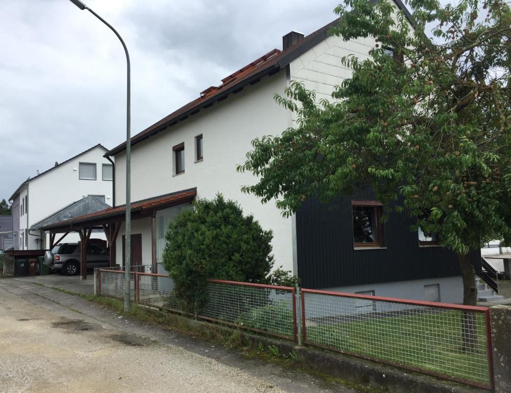 ein weißes und schwarzes Haus mit einem Baum und einem Zaun in der Unterkunft Komfort Wohn- und Ferienhaus JAKOBI in Reichertshofen