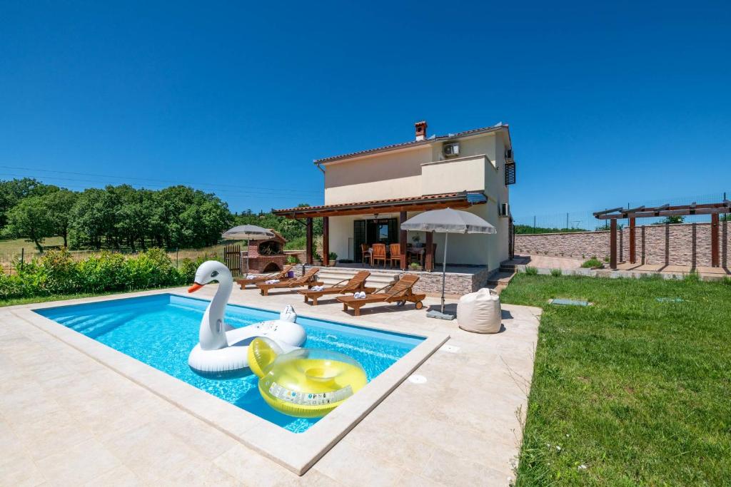 een huis met een zwembad met twee zwanen erin bij Villa Madonnina in Manjadvorci