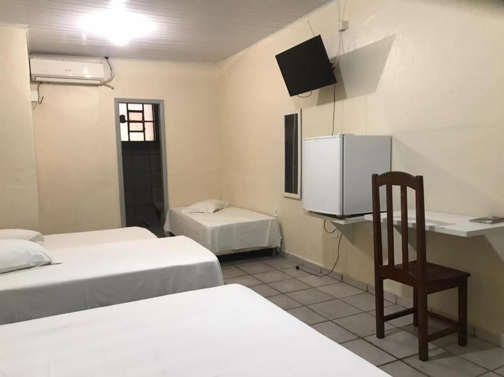 a room with two beds and a desk and a chair at Porto Seguro Hotel - Porto Velho in Porto Velho