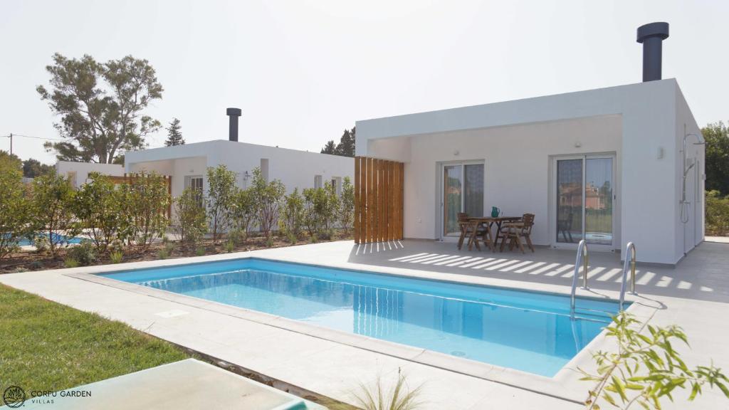 a villa with a swimming pool in front of a house at Corfu Garden Villas in Corfu