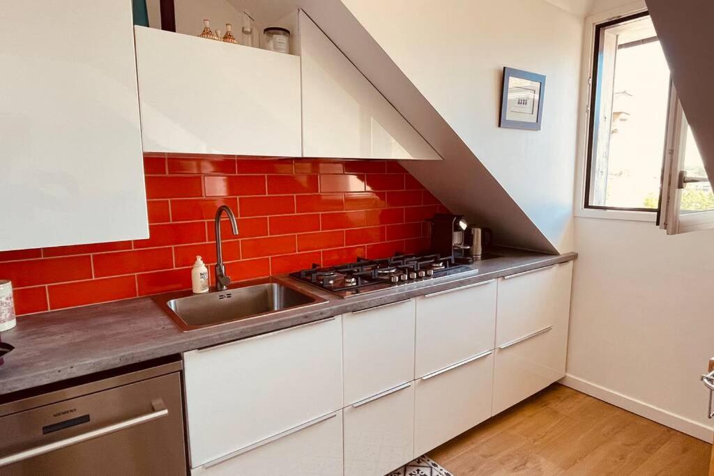 a kitchen with a sink and a red brick wall at **La Bretonnerie, bel appartement de standing in Concarneau
