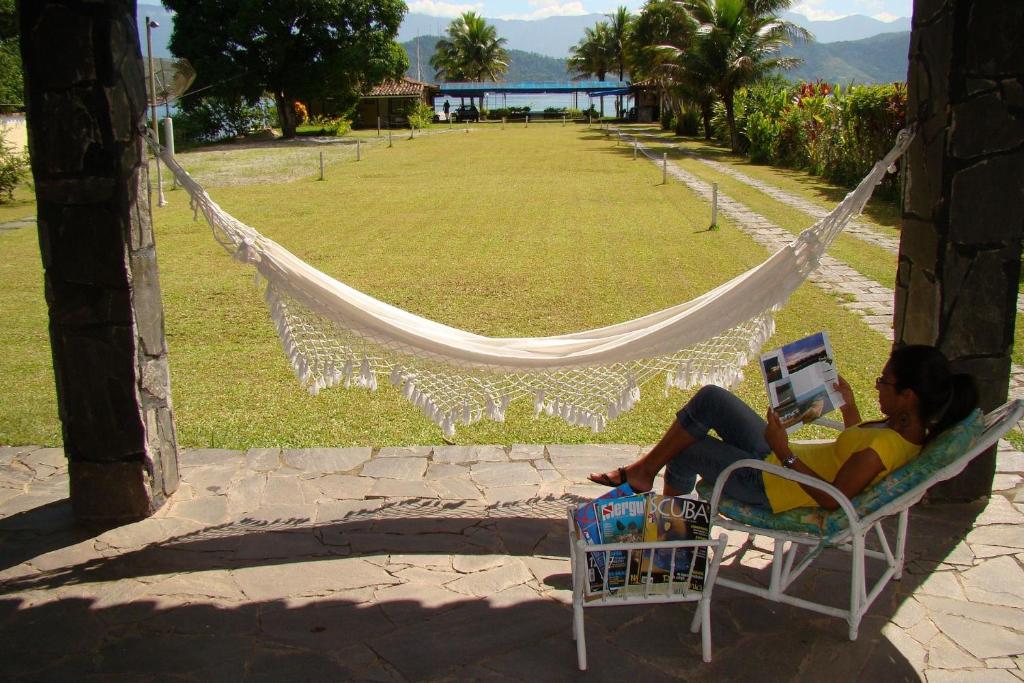 una mujer sentada en una hamaca en una silla con un ordenador portátil en Pousada Aquamaster Dive Center en Angra dos Reis