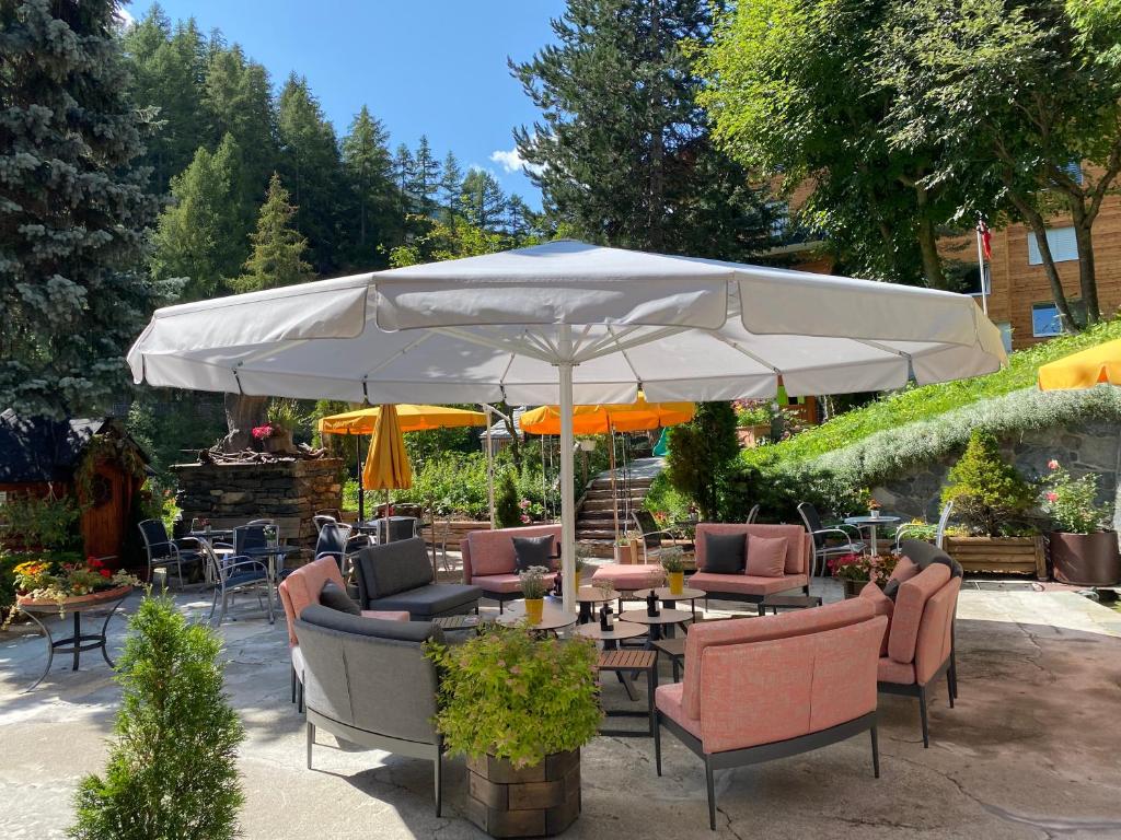 a patio with tables and chairs under an umbrella at Alpenblick in Zermatt