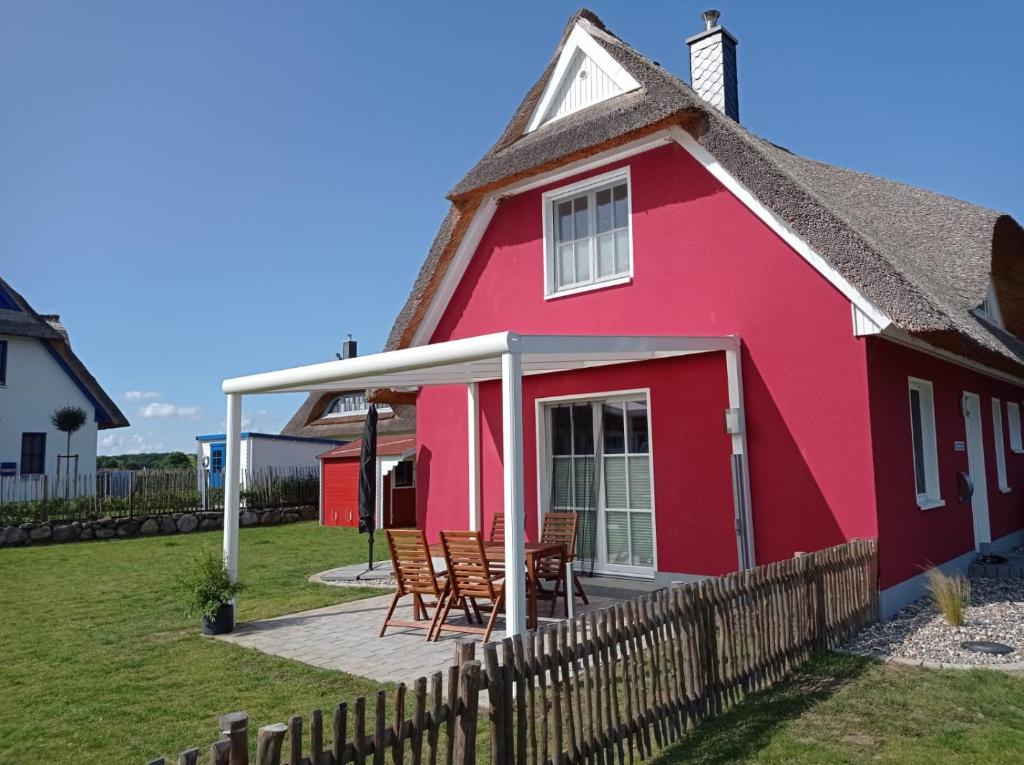 une maison rouge avec des chaises et une terrasse dans l'établissement Dat Papenboerger Hus, à Zierow