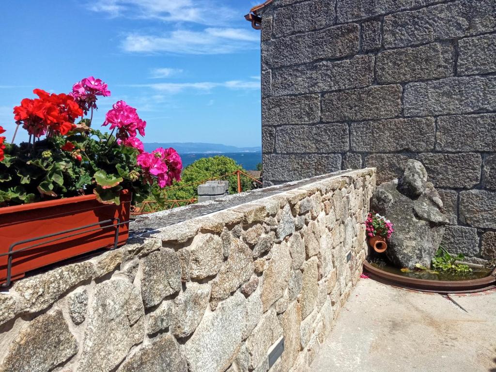 a stone retaining wall with flowers on it at O Iniño casita rural costera in O Grove