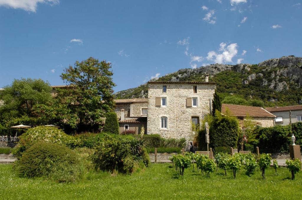 a large stone building in a field with trees at Restaurant et Chambres d'Hôtes La Ferme de Cornadel in Anduze