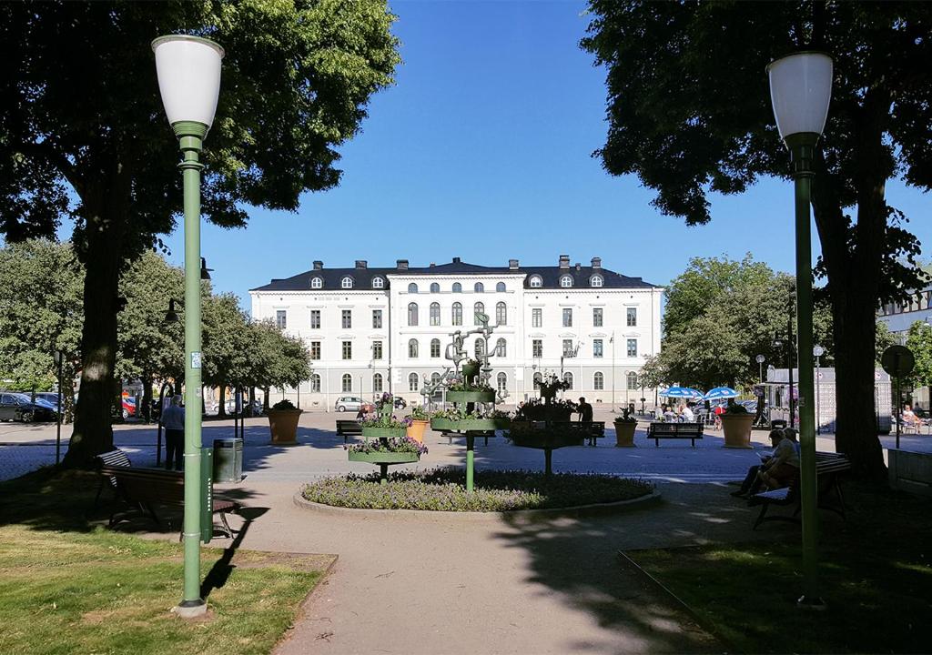 een groot wit gebouw met een standbeeld in een park bij Vänerport Stadshotell i Mariestad in Mariestad