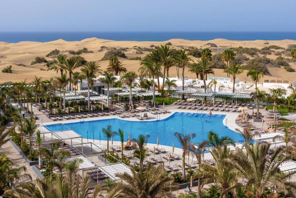 ein Luftblick auf ein Resort mit einem Pool und Palmen in der Unterkunft Hotel Riu Palace Maspalomas - Adults Only in Maspalomas