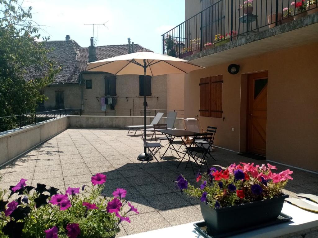 un patio con una mesa con sombrilla y flores en Quiétude et confort, en Tallard