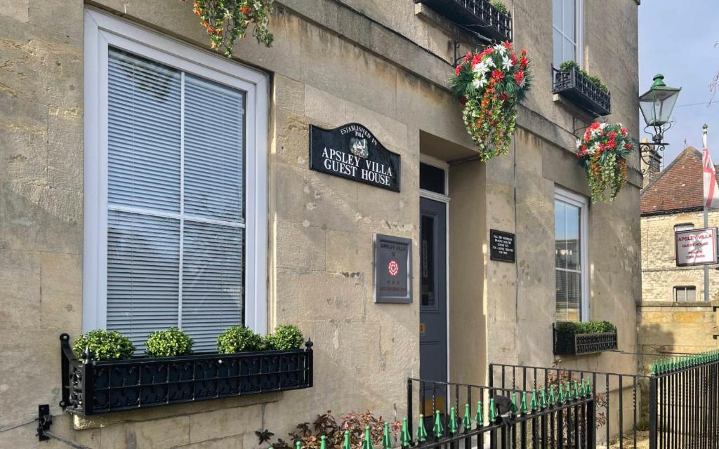 a building with potted plants and a sign on it at APSLEY VILLA GUEST HOUSE. in Cirencester