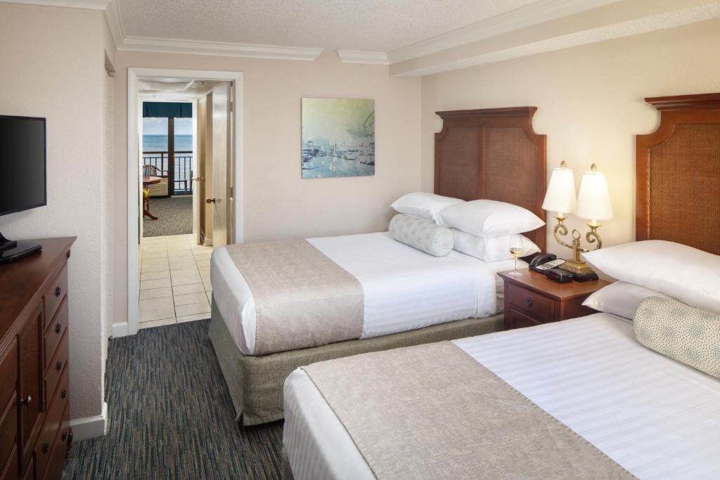 a hotel room with two beds and a television at Holiday Pavilion Resort on the Boardwalk in Myrtle Beach