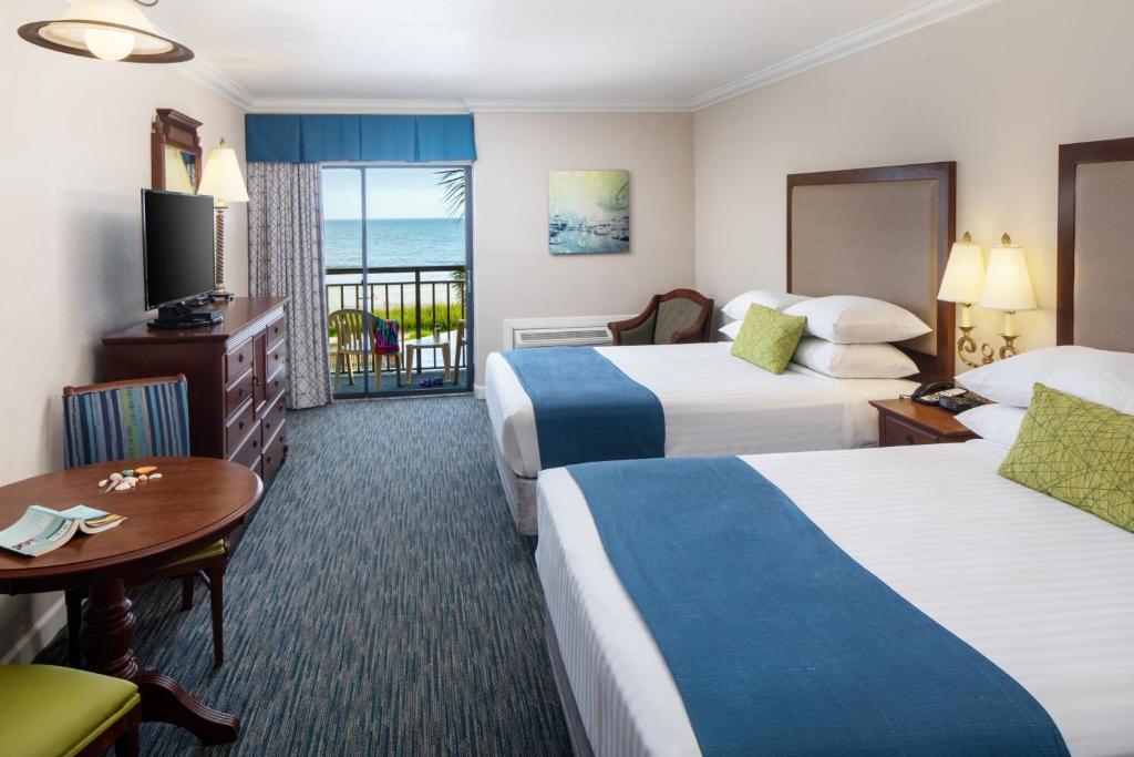 a hotel room with two beds and a balcony at Holiday Pavilion Resort on the Boardwalk in Myrtle Beach