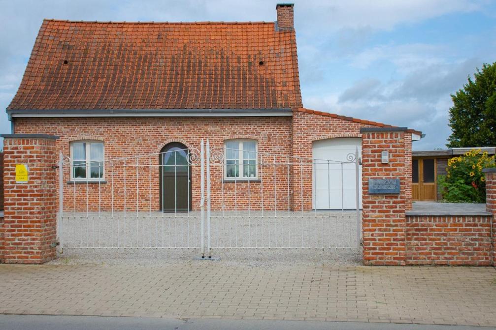 una casa di mattoni rossi con due porte bianche per il garage di Huis van de Koekuit a Moorslede