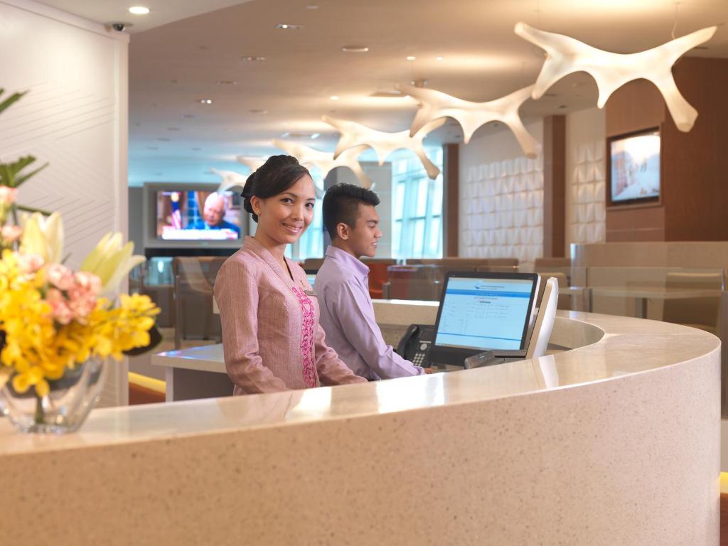 a man and a woman standing at a counter with a laptop at Sama Sama Express klia2 (Airside Transit Hotel) in Sepang