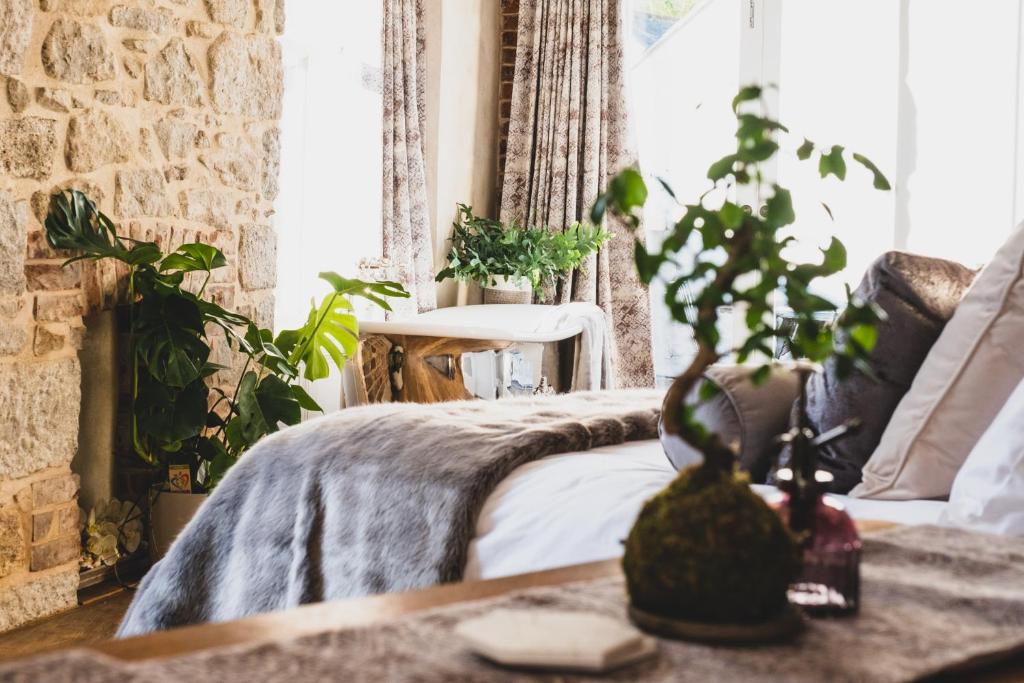 a bedroom with a bed and plants on a table at Host St Ives in St Ives