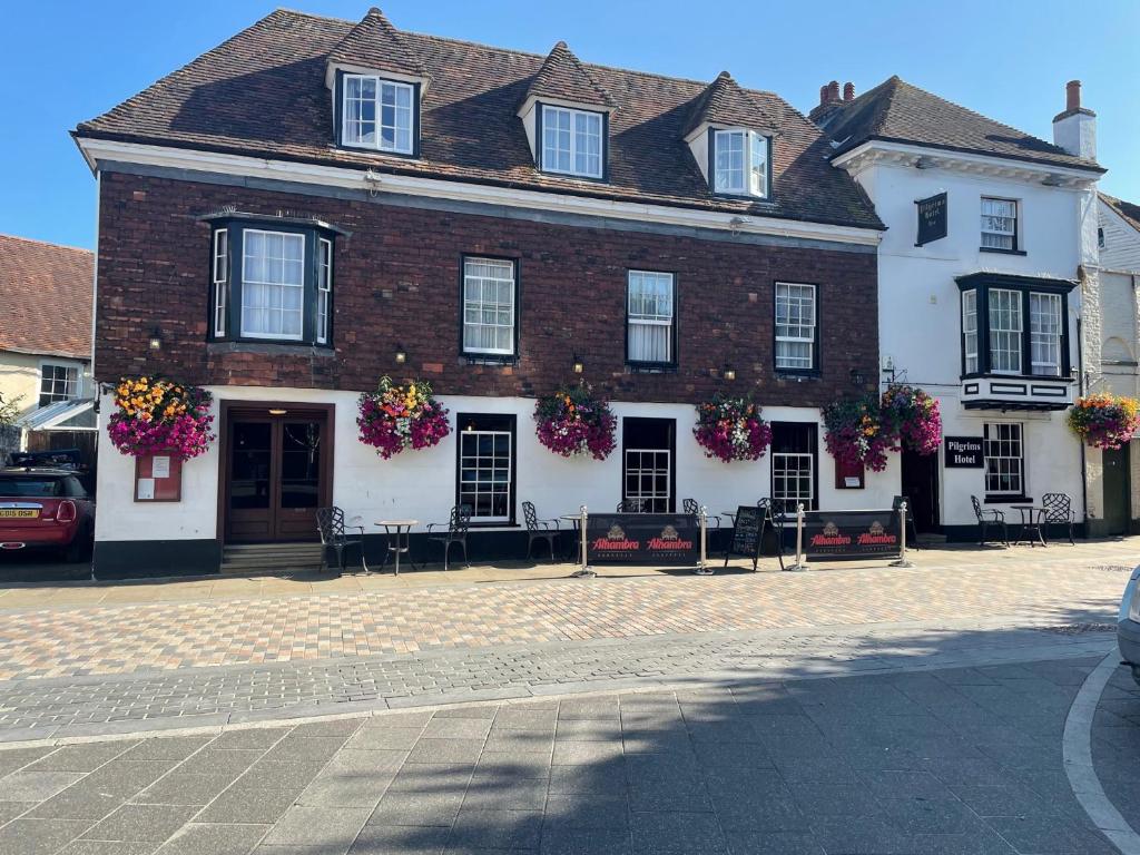 een groot bakstenen gebouw met bloemen op de ramen bij Pilgrims Hotel in Canterbury