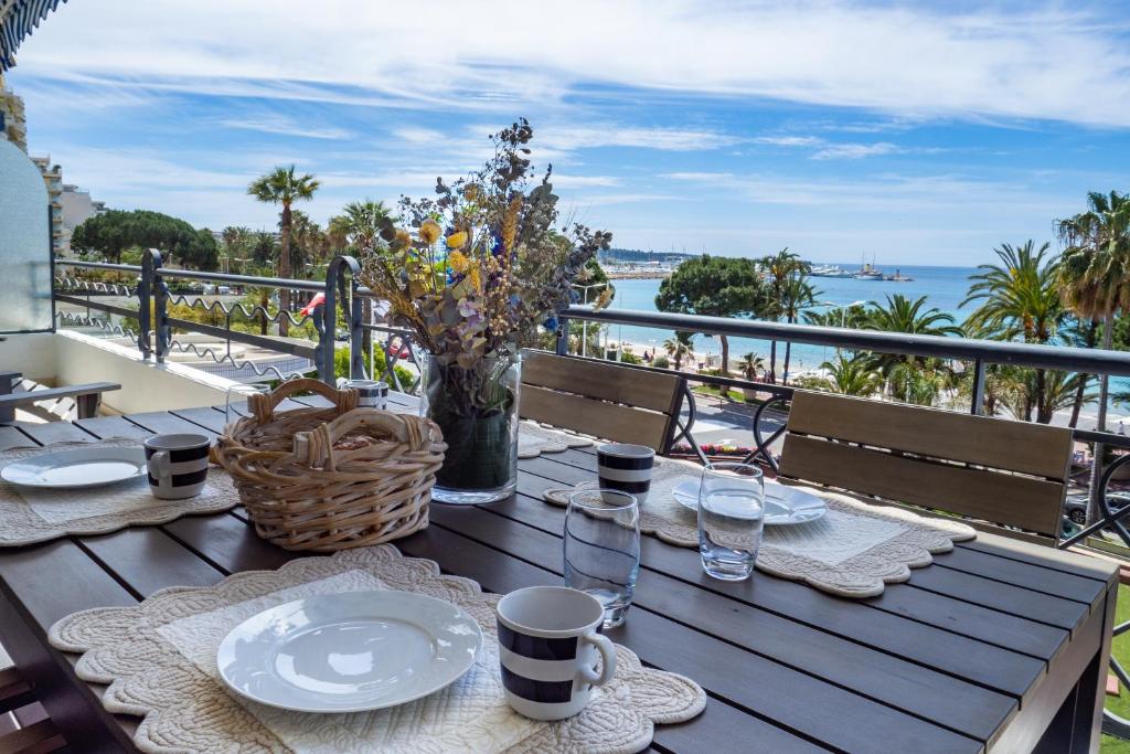 - une table en bois avec des assiettes de nourriture et une vue sur l'océan dans l'établissement Cannes Croisette Superbe 3P front de mer, à Cannes