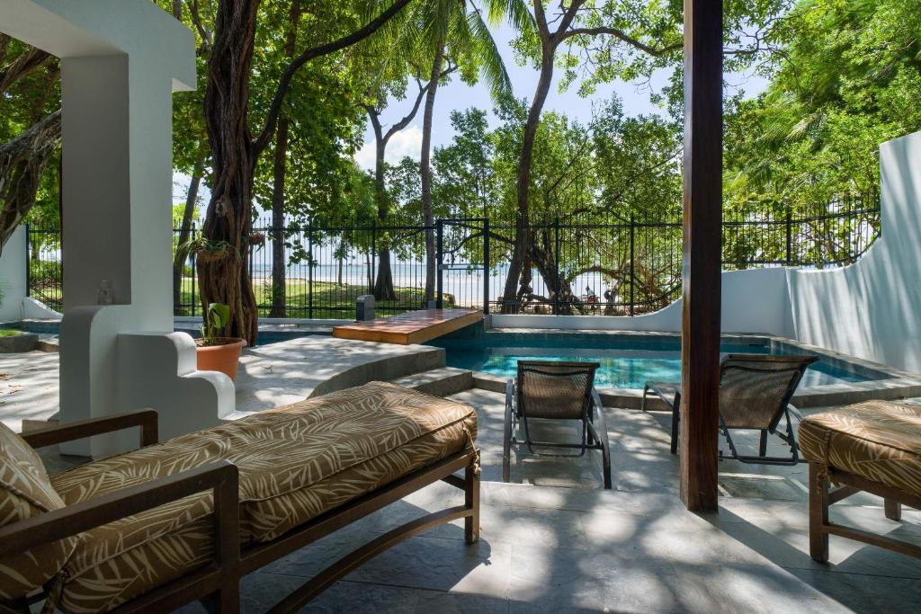 a patio with a pool and chairs and trees at Casa Woodbine Private House on Tamarindo Beach in Tamarindo