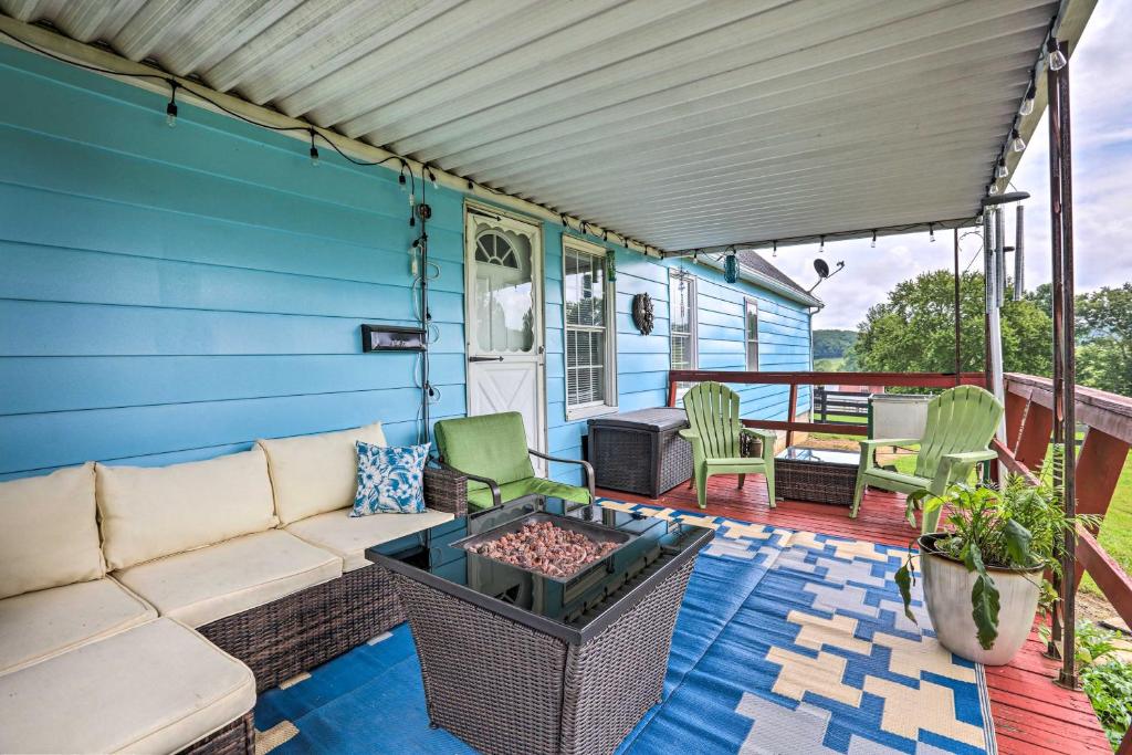 a blue house with a couch and chairs on a deck at Charming East Bernstadt Retreat Less Than 6 Acre Farm! in East Bernstadt
