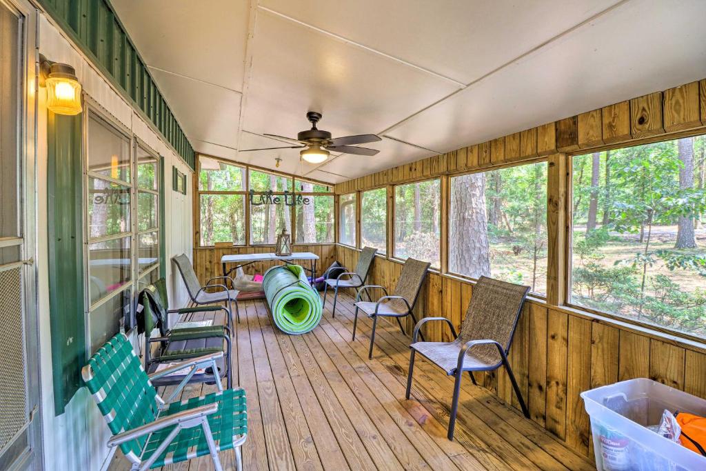 a screened porch with chairs and a table and a ceiling fan at Higden Hideaway on Lake Pets and ATVs Allowed! in Fairfield Bay