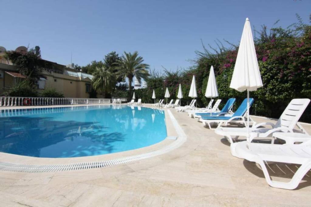 eine Reihe von Liegestühlen und ein Pool mit Sonnenschirmen in der Unterkunft Villa with pool near the sea in Konaklı