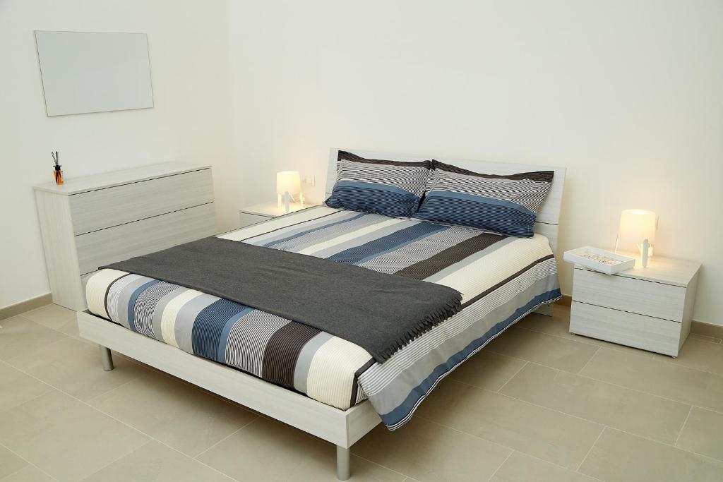 Scirocco Guest House في برينديسي: غرفة نوم بسرير كبير مع مواقف ليلتين