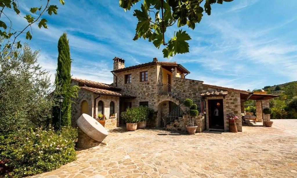 a large stone house with a stone driveway at La Macina di Bettona in Bettona