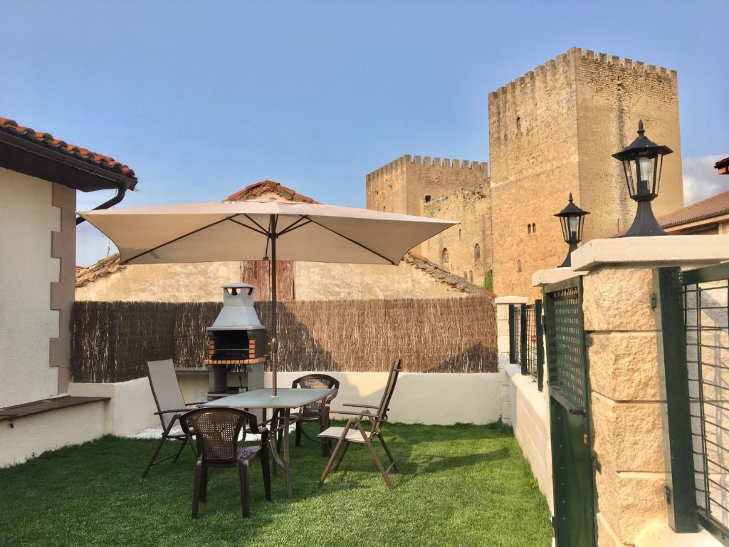 a table and chairs with an umbrella in front of a castle at La Casita del Alcázar in Medina de Pomar