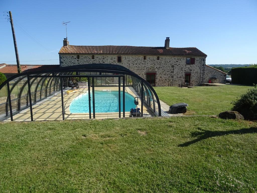 a pool in front of a house with a glass door at La Lauriére in Treize-Vents