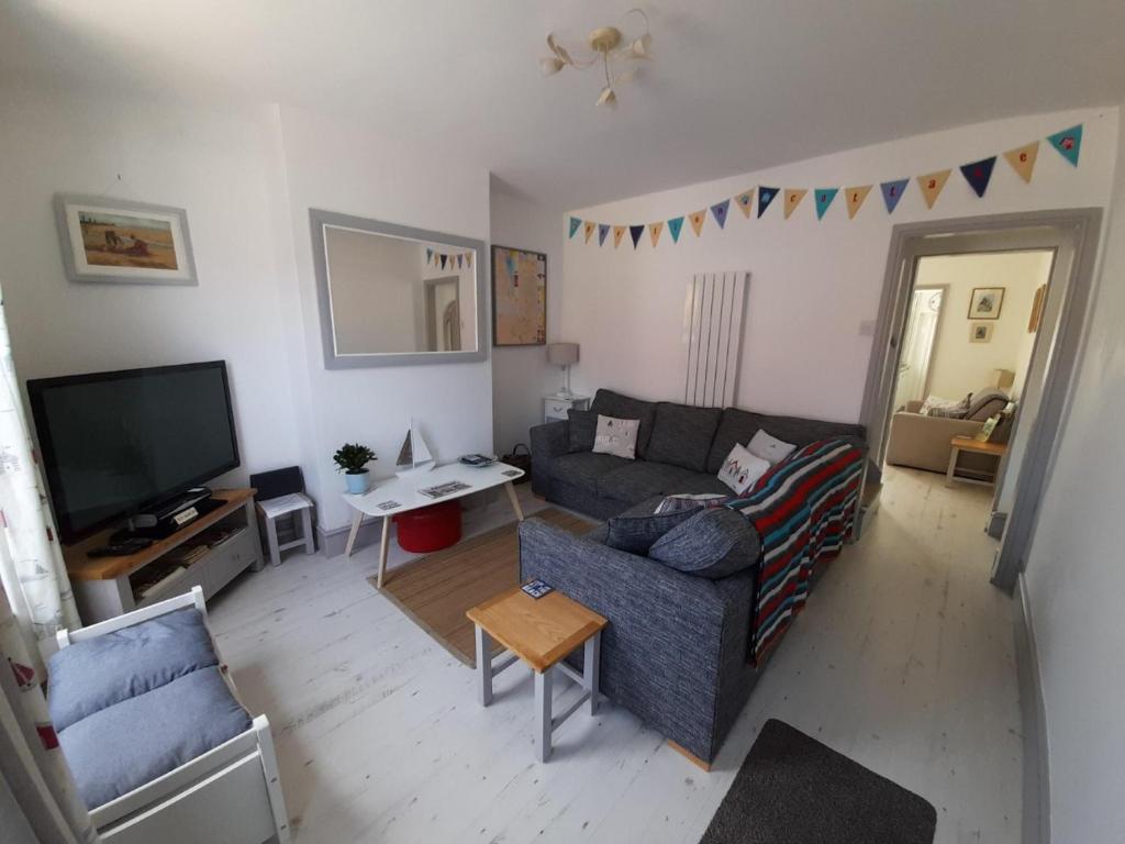 a living room with a couch and a tv at 'Pavilion Cottage' next to Gorleston beach with sea views - pet friendly! in Gorleston-on-Sea