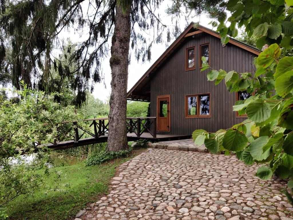 a house with a tree and a stone walkway at Sauleskalns in Zaķumuiža