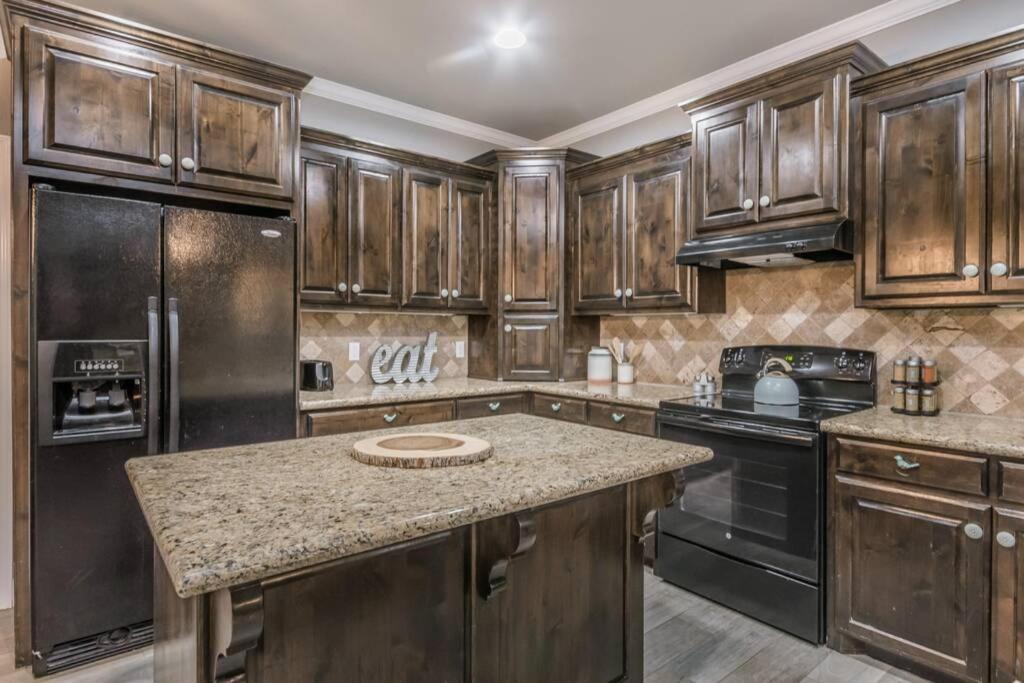 a kitchen with wooden cabinets and a granite counter top at Cheerful 3 Bedroom Home, King Bed, 10 min from Palo Duro Canyon, Fireplace, Washer Dryer in Canyon