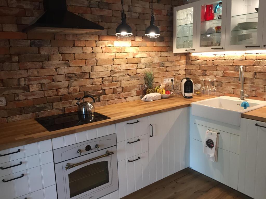 una cocina con armarios blancos y una pared de ladrillo en Apartament z ogrodem, en Starogard Gdański