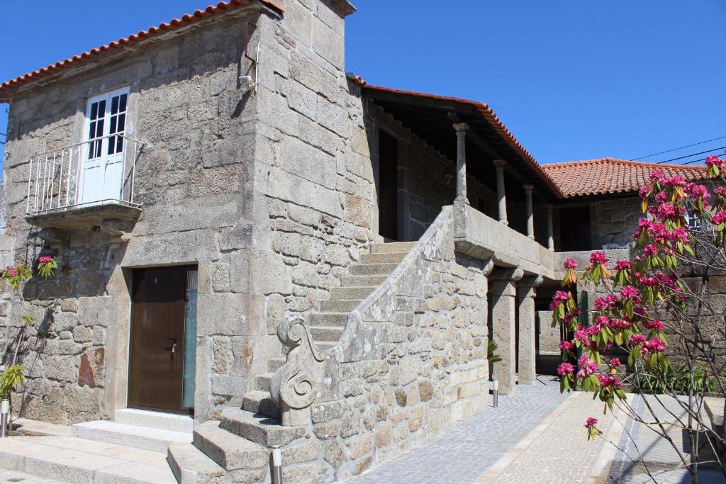 a stone building with pink flowers in front of it at Alojamento Local Boega Hotel - Casas Boega I e II in Gondarém