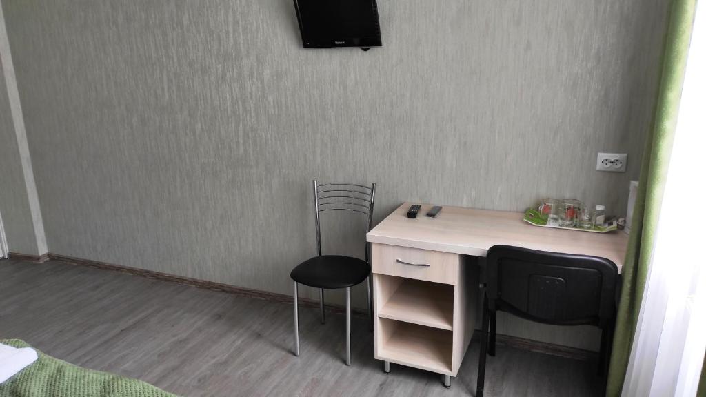 een kamer met een bureau met 2 stoelen en een televisie bij Вилла ALEX in Vinnytsya
