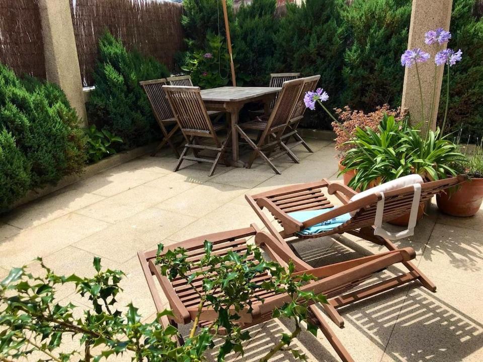 een patio met een tafel, stoelen en bloemen bij Apartamento céntrico en Finisterre in Fisterra